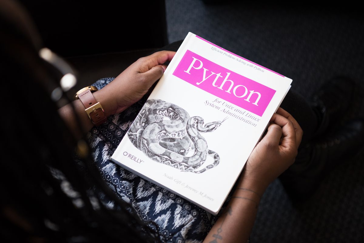 A person reading a Python programming book, illustrating the beginner path from Excel to learning Python for data analysis