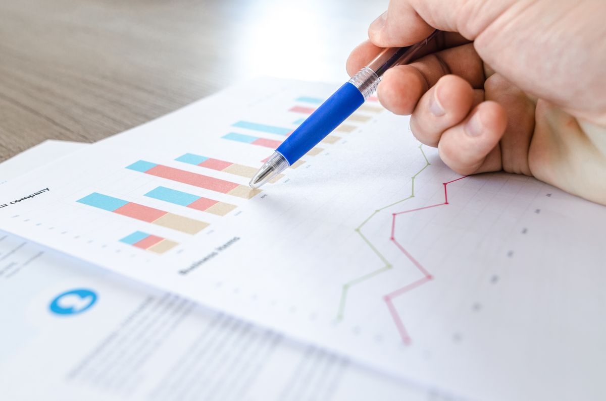Colorful stacked bar chart and line trend on a printed financial report, with a pen pointing at a data point — illustrating how lookups surface specific values from a larger dataset